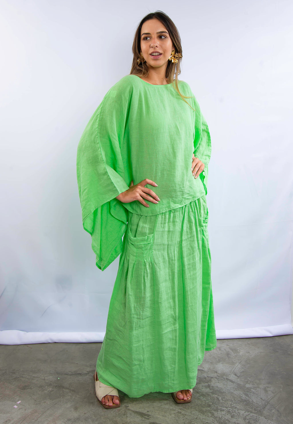 Modelo feminina em look verde vibrante, com blusa ampla e saia comprida em linho.