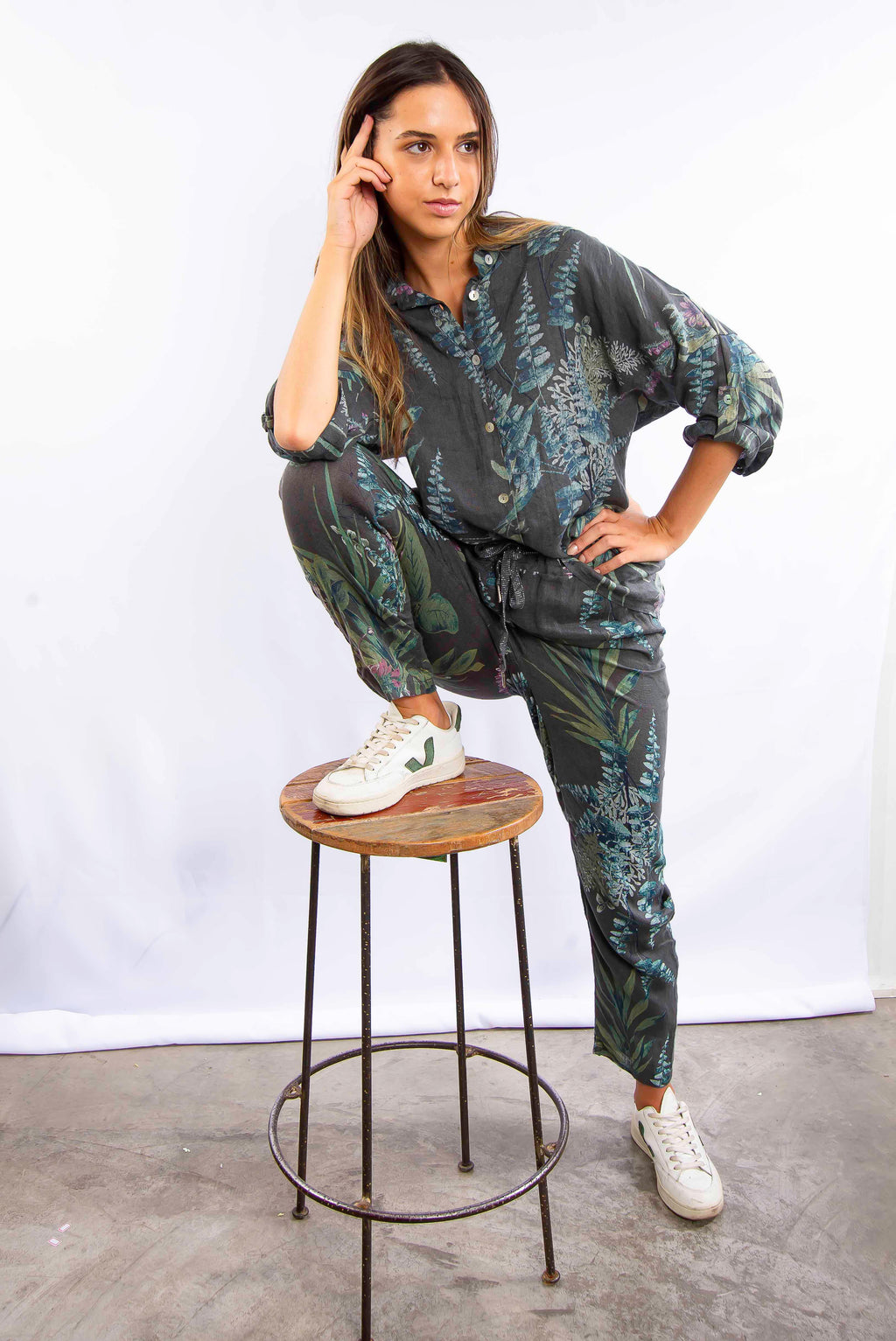 Mulher sentada em banco vestindo conjunto estampado azul, com estilo moderno e confortável.