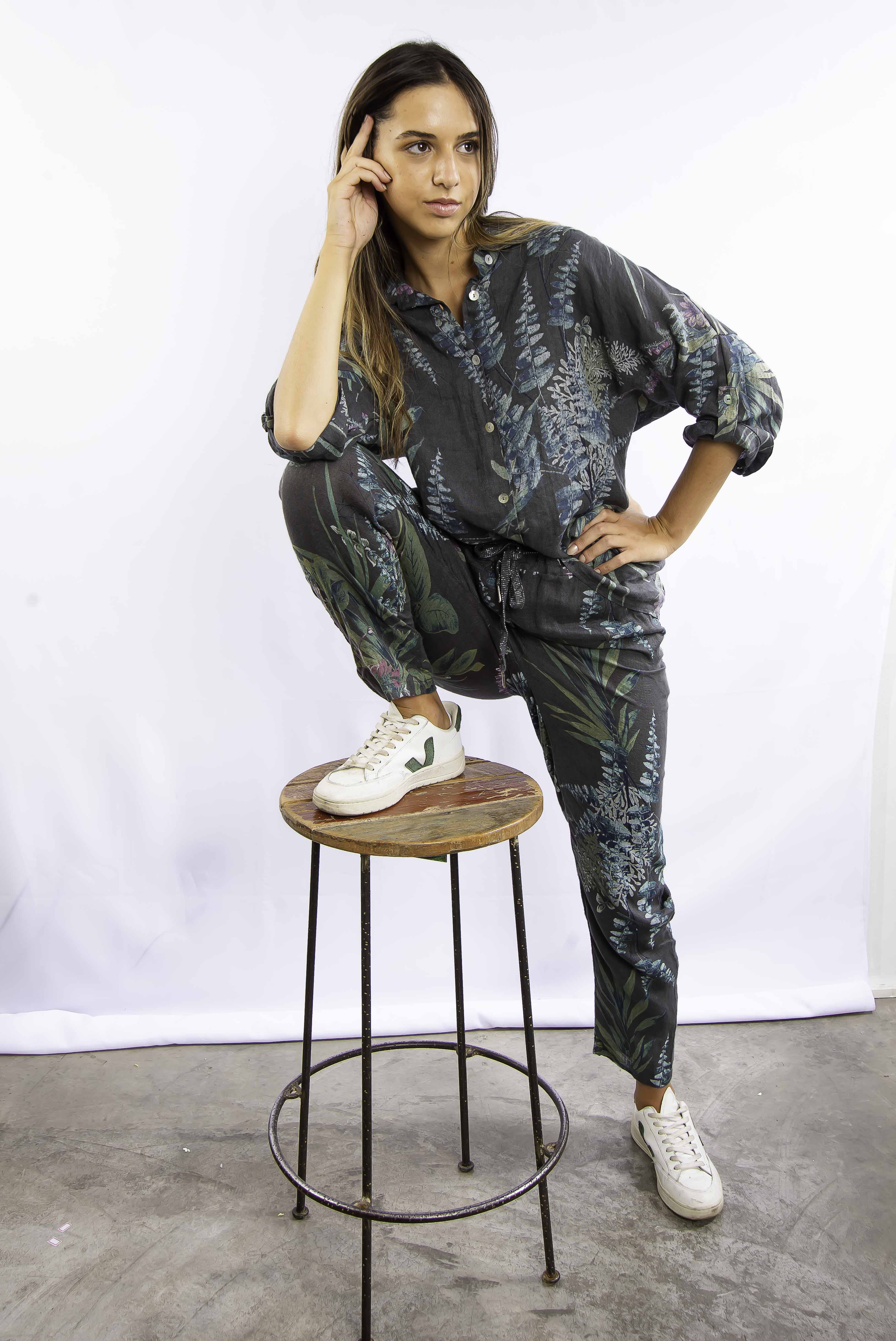 Mulher sentada em banco vestindo conjunto estampado azul, com estilo moderno e confortável.