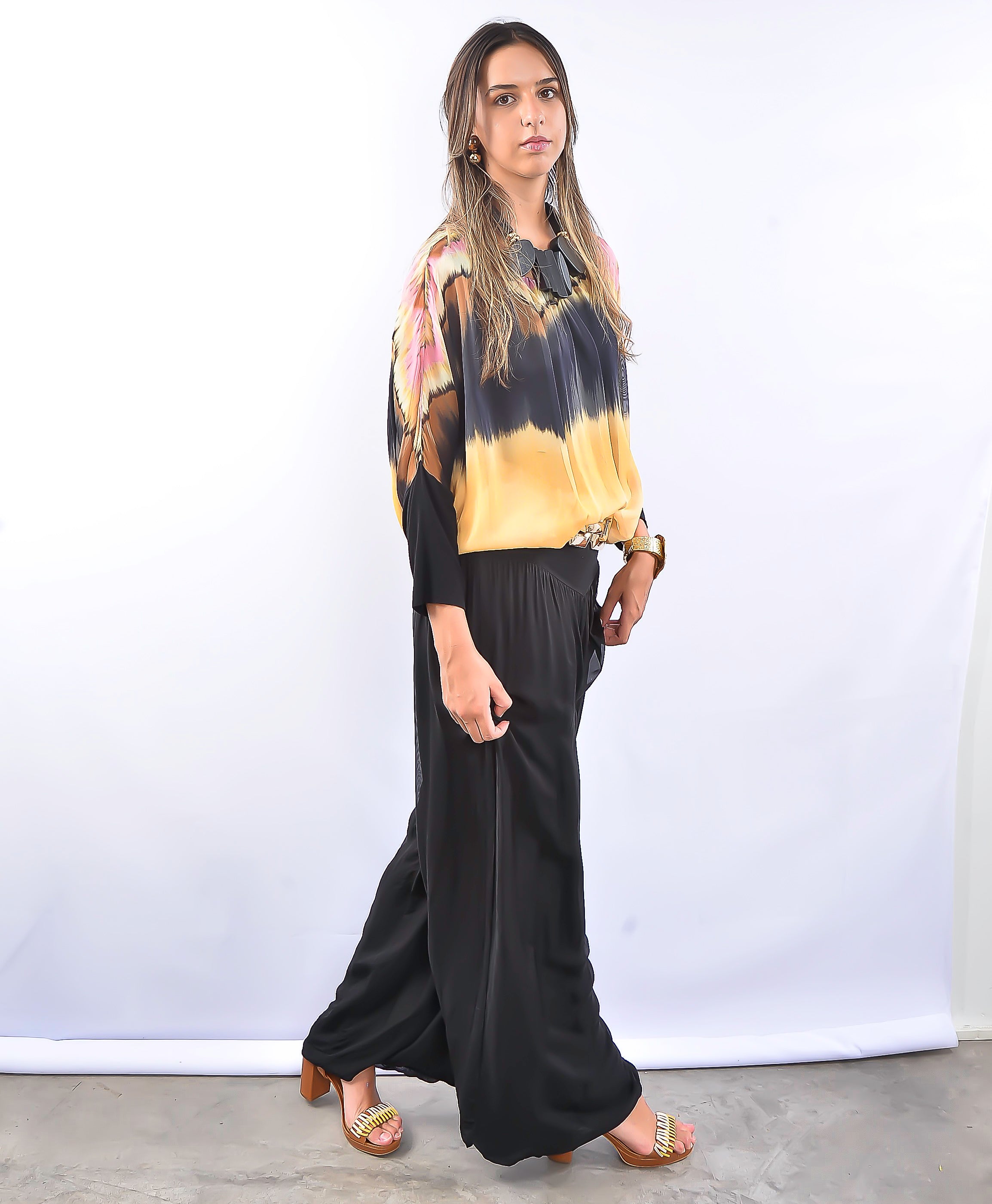 Modelo usando conjunto feminino com blusa estampada em preto e amarelo e calça preta ampla