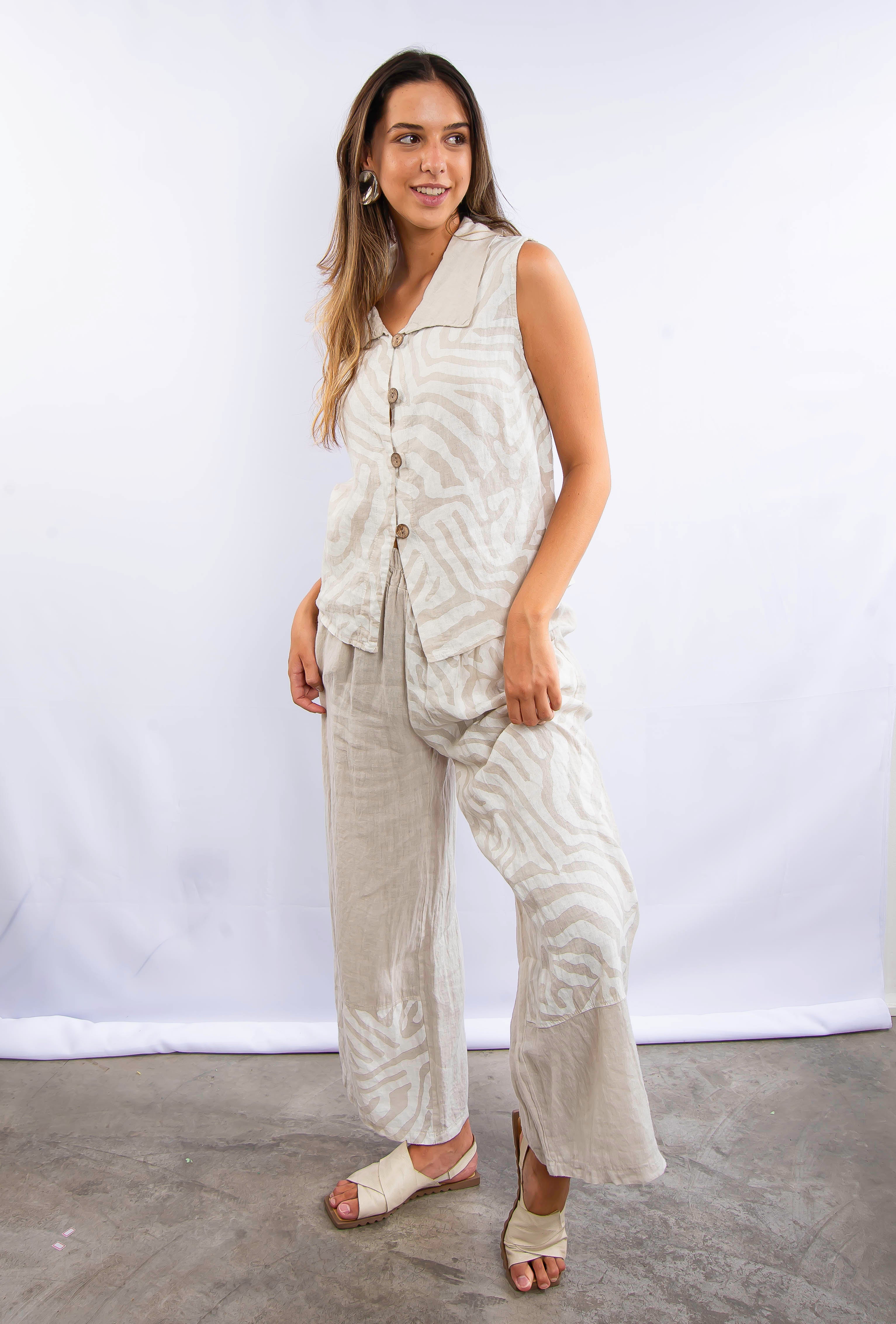 Mulher vestindo conjunto feminino em linho off-white, sem mangas e calça fluida.