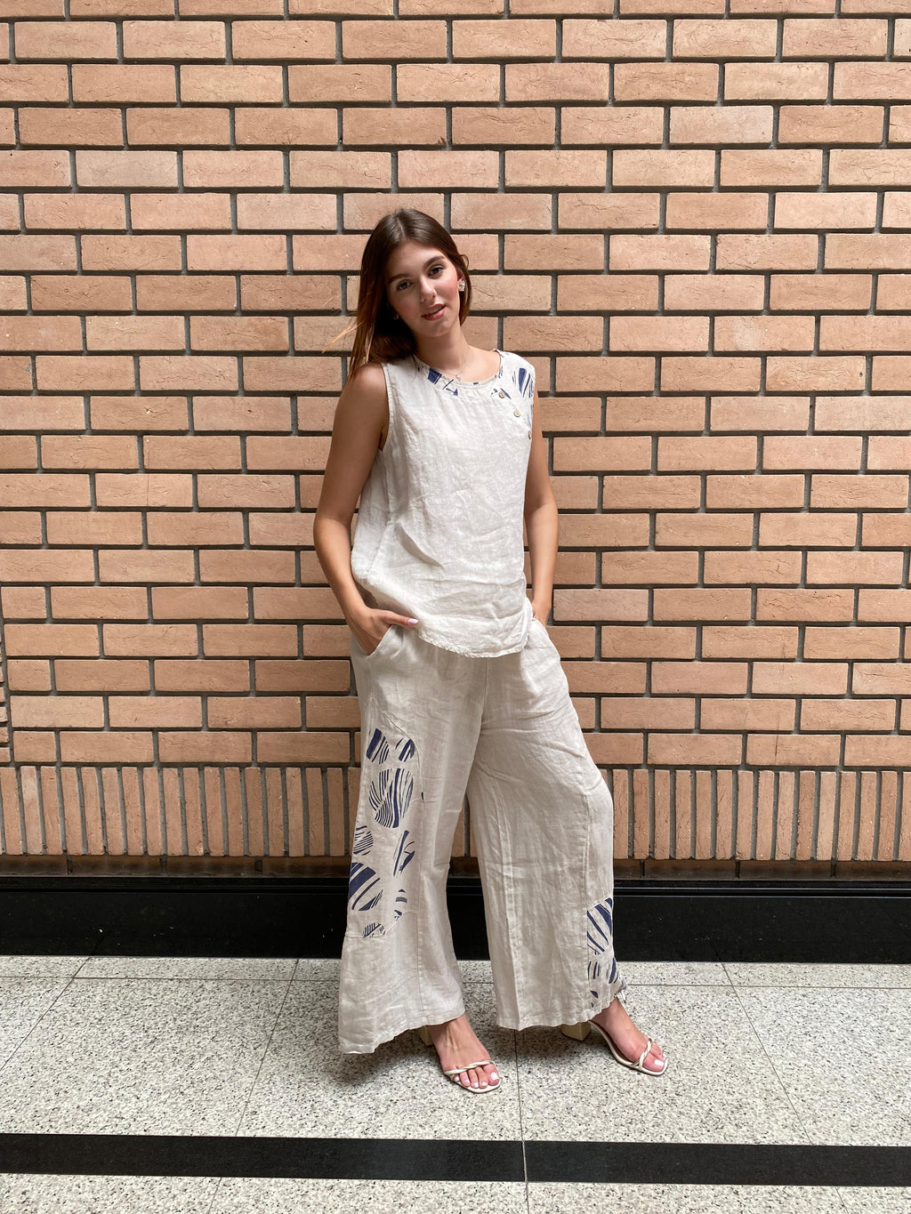 Mulher usando Conjunto Positano em 100% linho italiano, blusa sem mangas e calça reta.