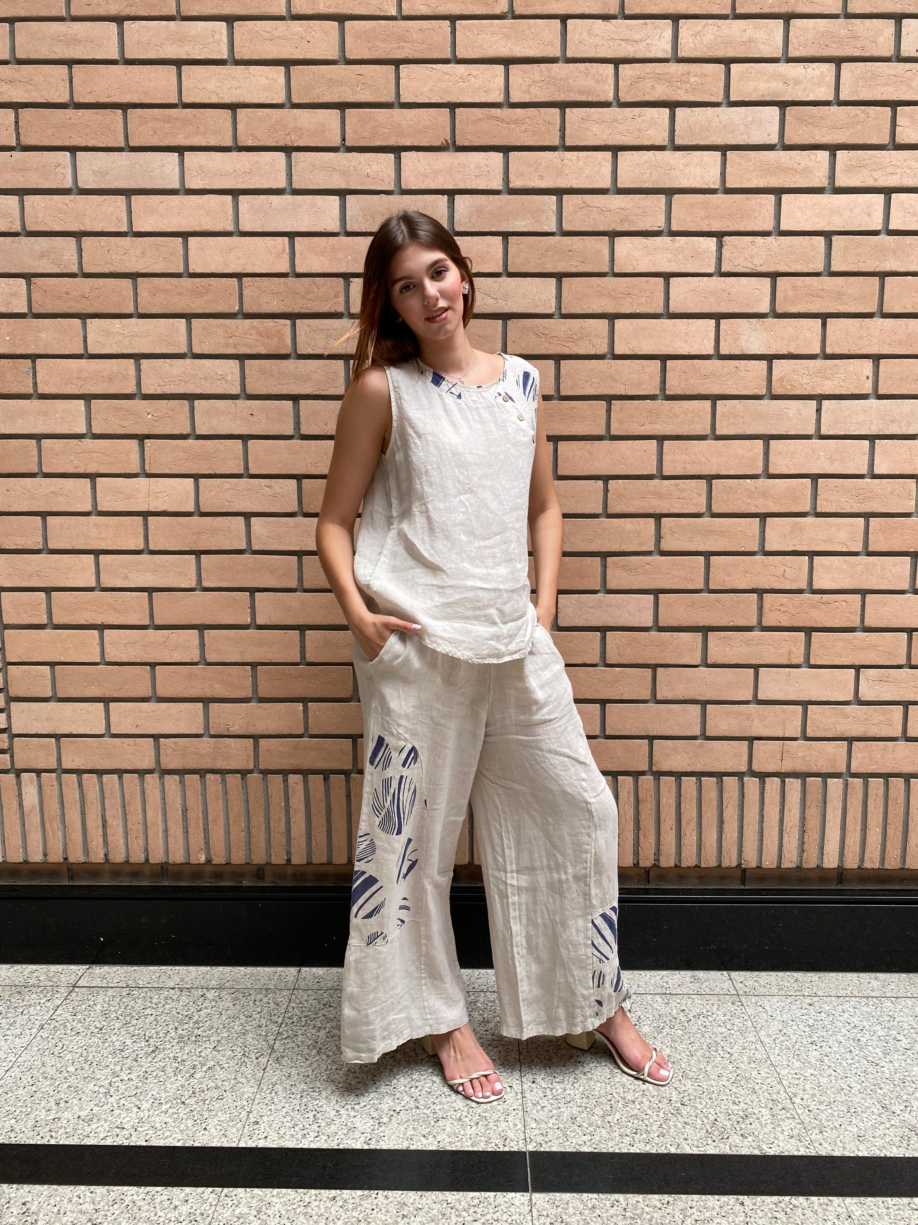 Mulher usando Conjunto Positano em 100% linho italiano, blusa sem mangas e calça reta.
