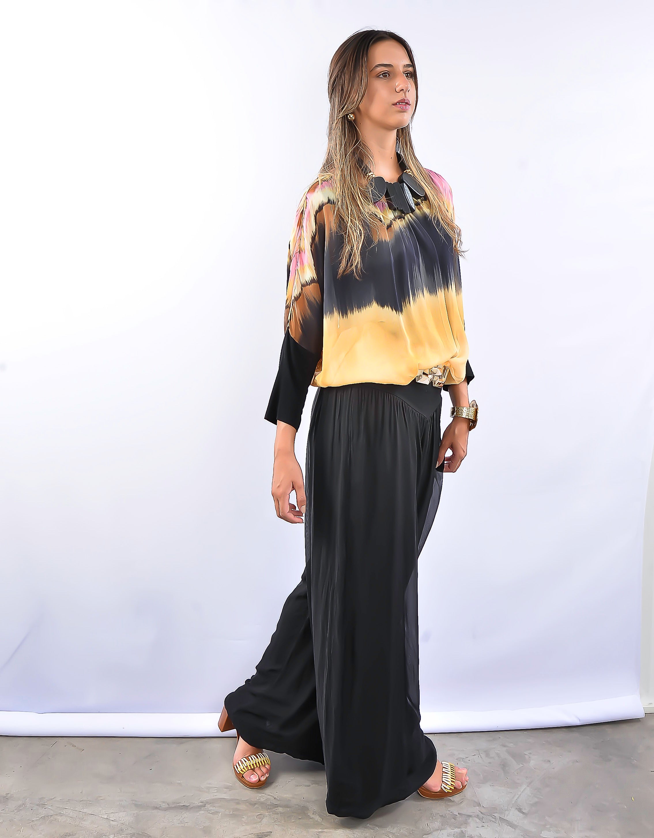 Look moderno com blusa soltinha estampada em tons escuros e calça pantalona preta