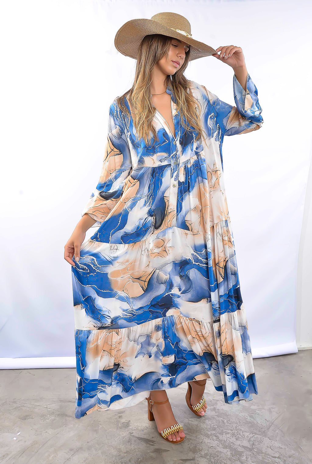 Mulher com vestido estampado azul, estilo boho chic, em pose descontraída