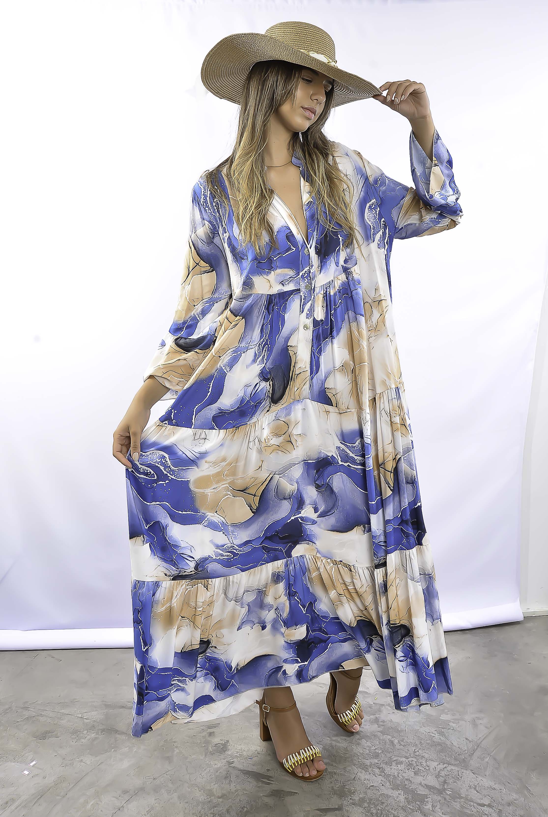 Mulher com vestido estampado azul, estilo boho chic, em pose descontraída