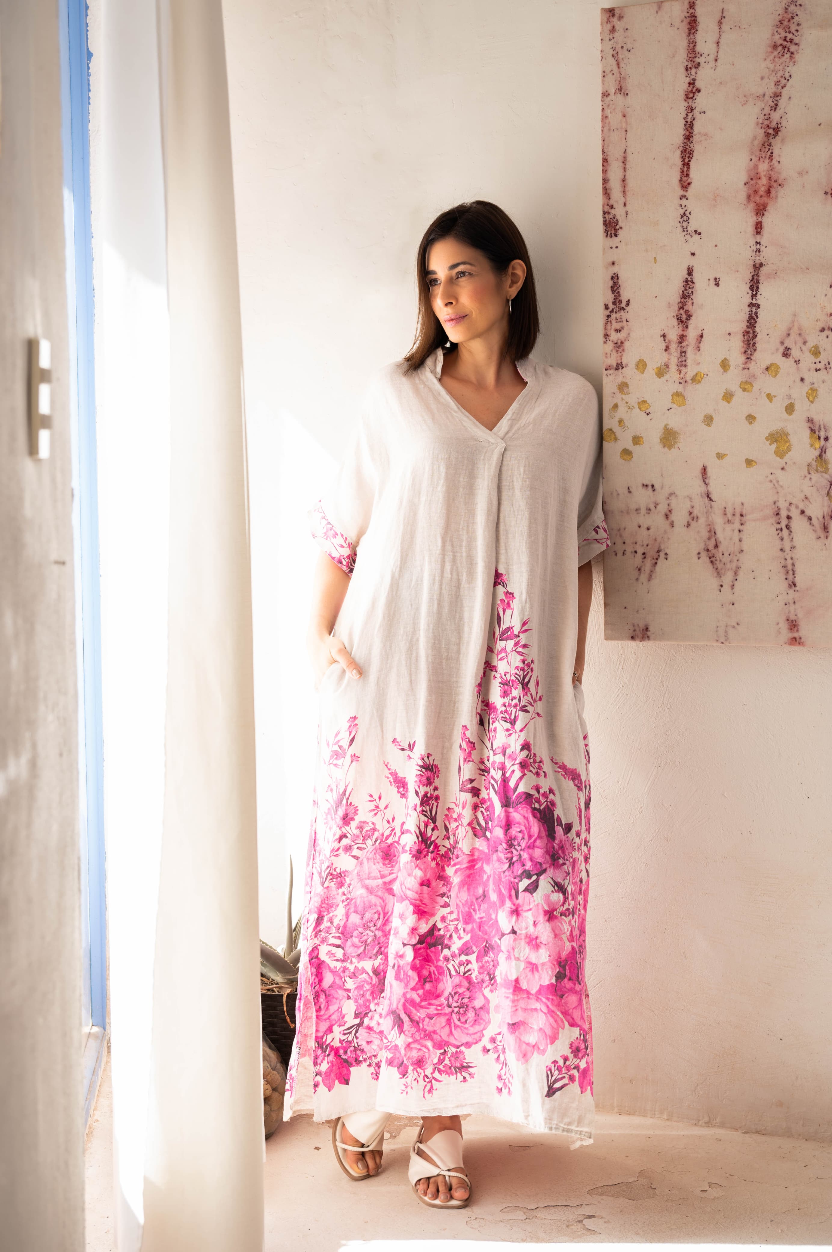 Mulher usando Vestido Calábria longo em linho branco com estampa rosa.