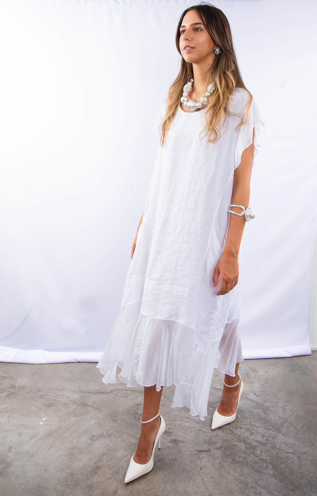 Modelo feminina desfilando em vestido branco sofisticado e moderno.
