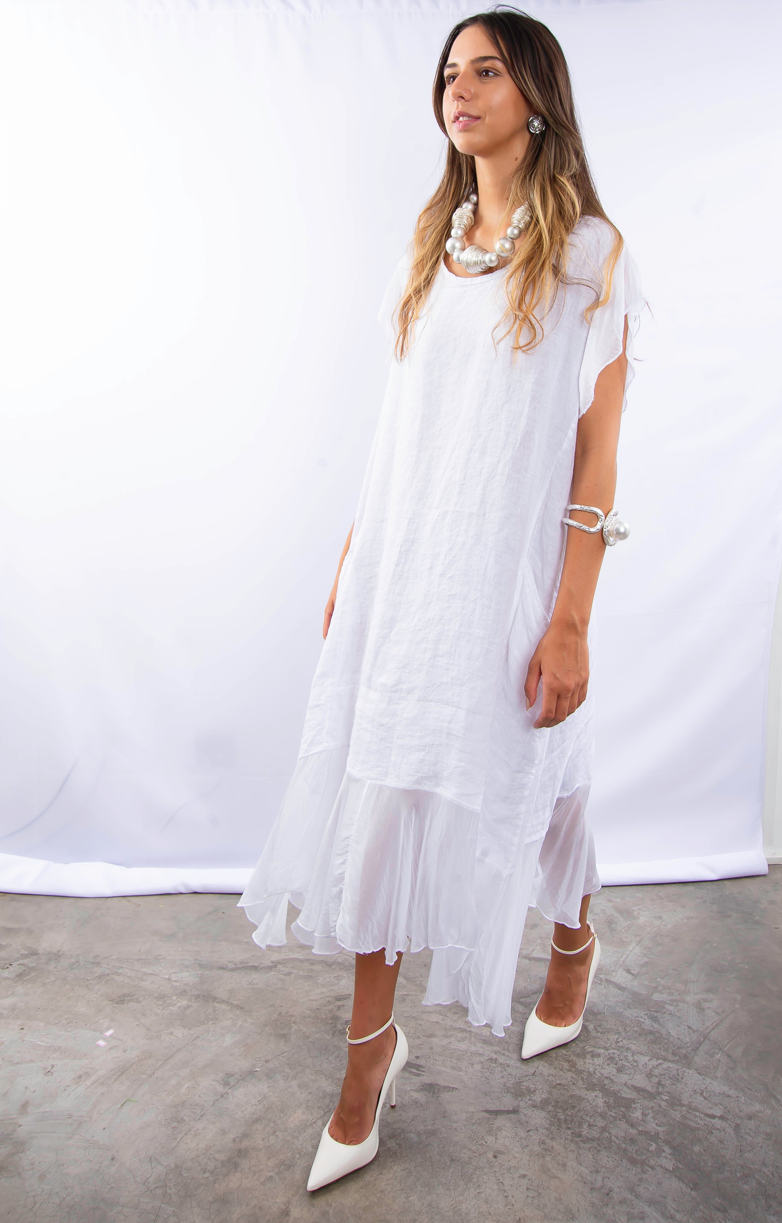 Modelo feminina desfilando em vestido branco sofisticado e moderno.