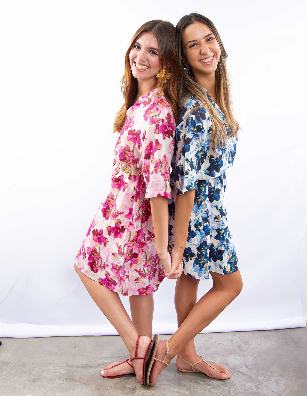 Duas mulheres usando vestidos florais de linho italiano nas cores rosa e azul.