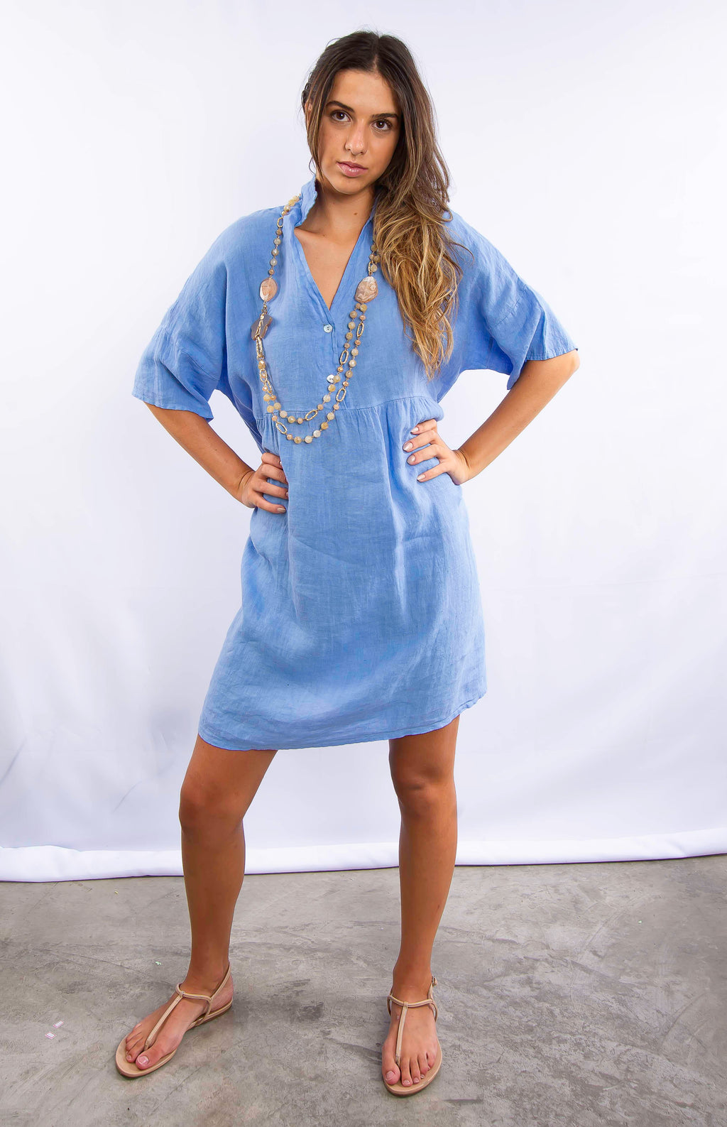 Vestido jeans azul curto visto de lado em modelo feminina.