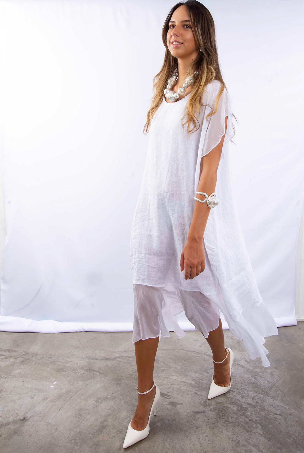 Mulher usando vestido longo branco de linho e seda, com design elegante e minimalista.