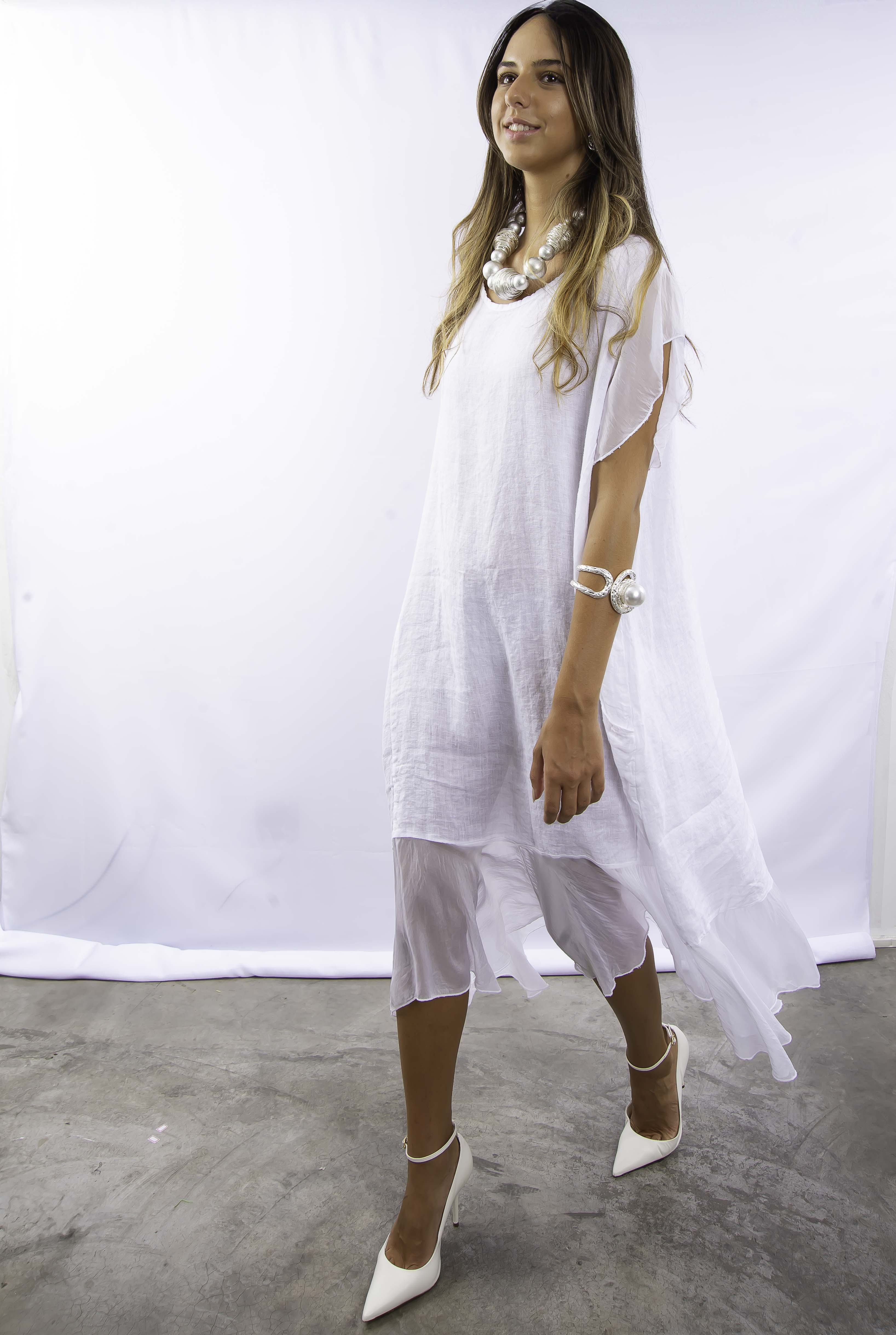 Mulher usando vestido longo branco de linho e seda, com design elegante e minimalista.