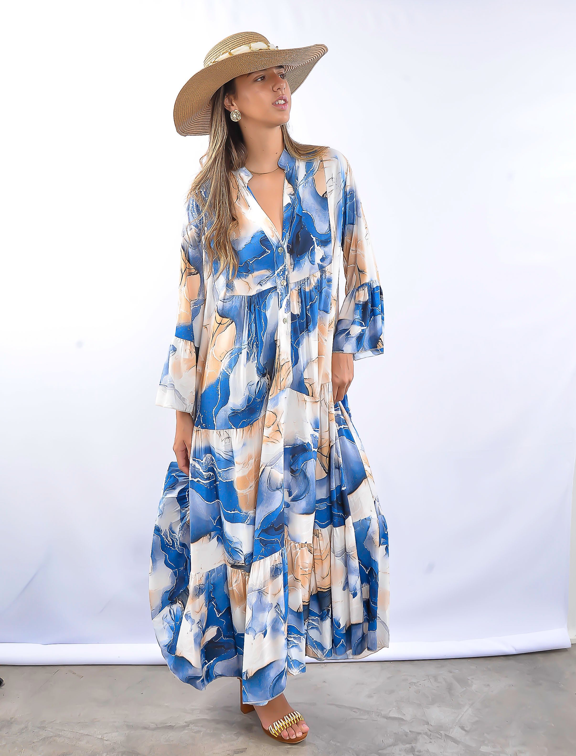 Modelo usando vestido longo estampado azul e branco com chapéu de palha.