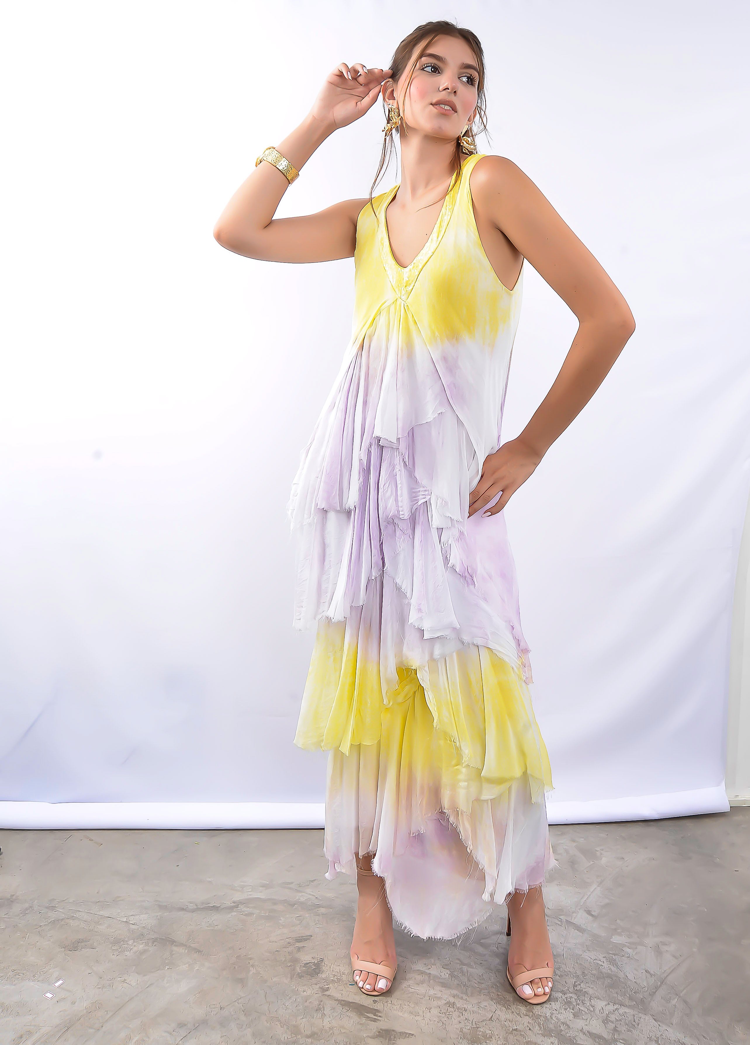 Modelo usando vestido longo fluido em tons de amarelo e lilás, com babados.