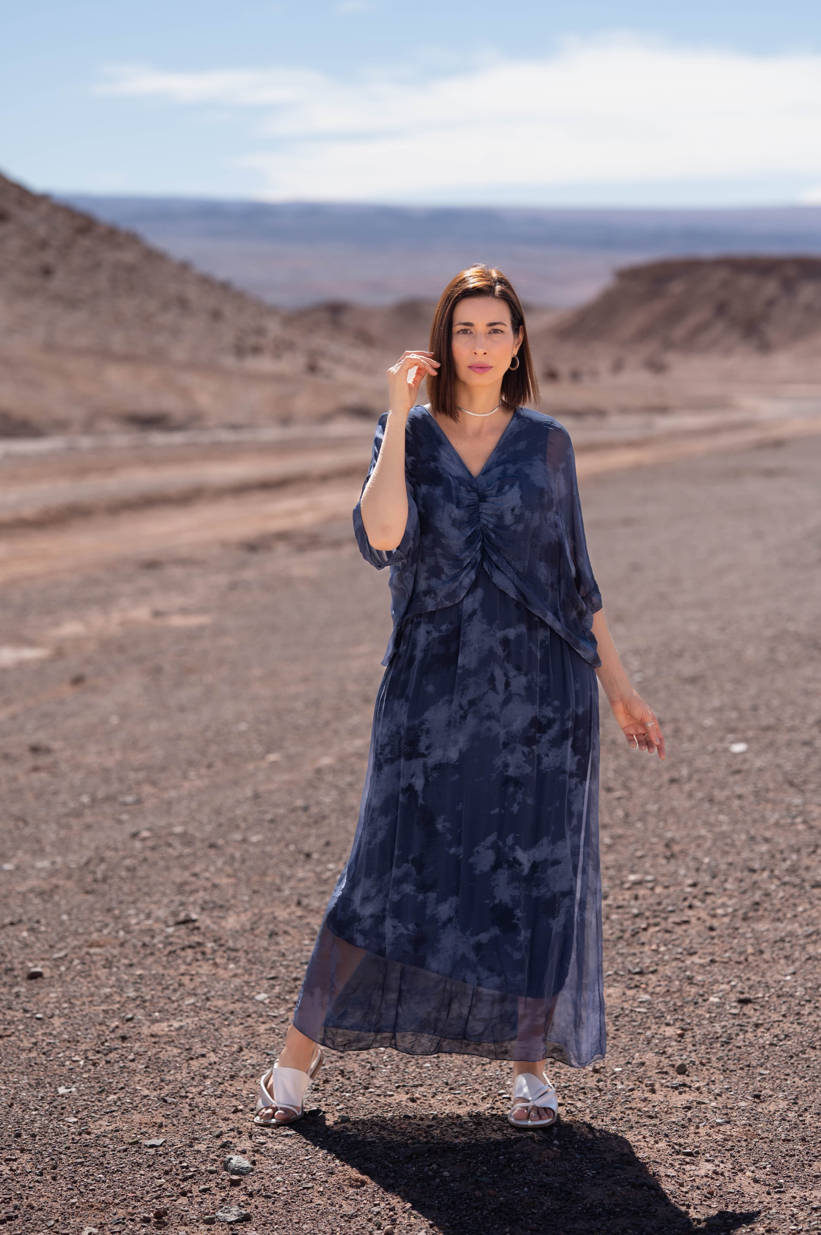 Mulher usando vestido longo azul Molise em linho italiano no deserto.